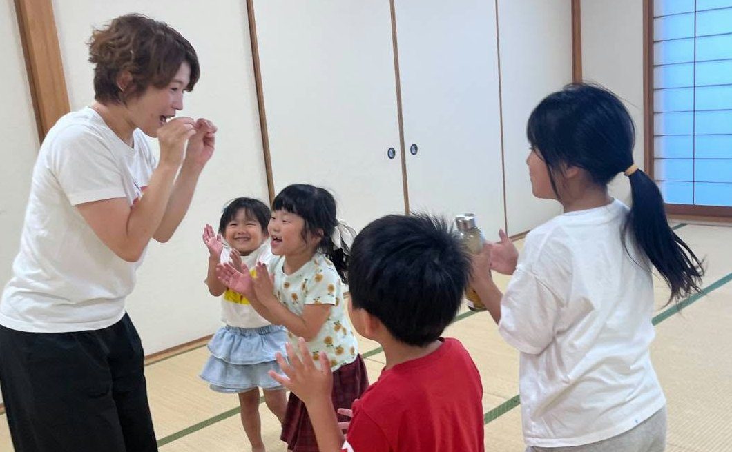 講師と一緒に笑顔で手をたたく子どもたち